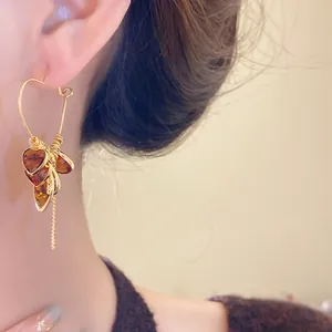 Detail view of a vintage heart-shaped amber earring with premium gold plating on model's ear.