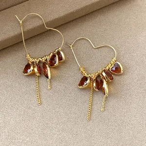 Macro detail of vintage 18K gold plated heart hoop earrings with amber teardrop charms