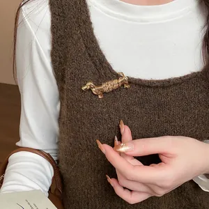 Gros plan d'une broche en forme de teckel doré épinglée sur un gilet en maille marron