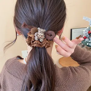 Close-up of a brown fabric hair scrunchie with a plush leopard print bear charm