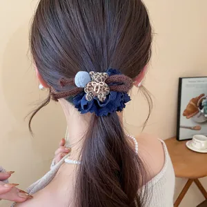 Close-up of leopard flocked bear hair tie with blue pom-pom and bow detail