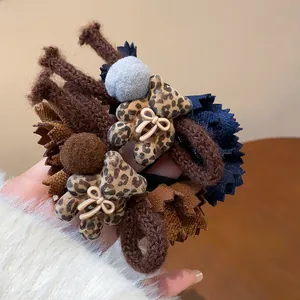 Close-up of leopard print flocked bear hair ties with fabric lace and pom-poms
