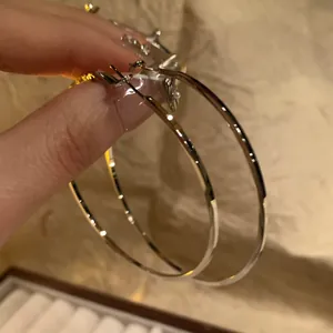 Large minimalist silver oval hoop earrings featuring a polished metallic finish for women
