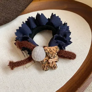 Detail shot of navy blue ruffled lace hair tie with flocked leopard bear and gray pom-pom