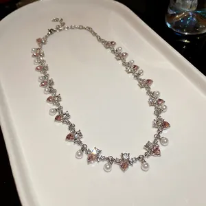 Detailed view of rhinestone heart pearl necklace with pink crystals on white tray
