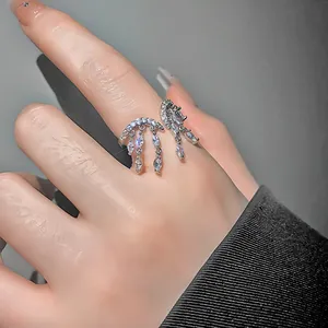 Primer plano de un elegante anillo abierto de flecos de circón plateado en el dedo, fino.