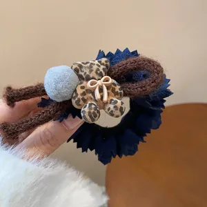 Close-up of navy blue hair tie with leopard flocking bear and grey pom-pom detail.