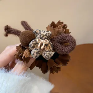 Detailed view of brown leopard print bear hair tie with plush fabric lace petals