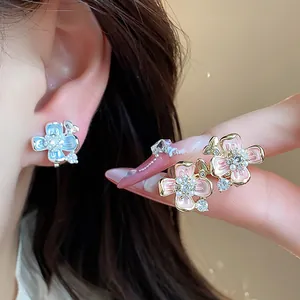 Close-up detail of 18k gold plated pink and blue enamel flower clip-on earrings