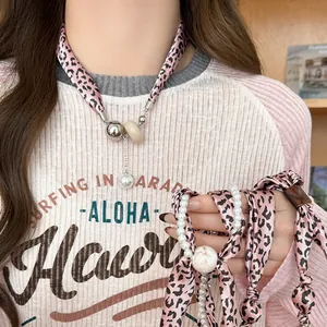Gros plan détaillé du collier écharpe en soie léopard rose avec perle élégante