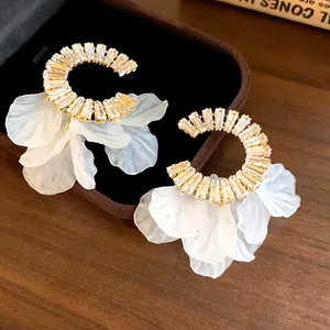 Dettaglio di eleganti orecchini in zirconia a forma di C con nappe a petalo bianco lucido