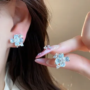 Detailed view of elegant 18k gold plated blue flower clip-on earrings with pearls