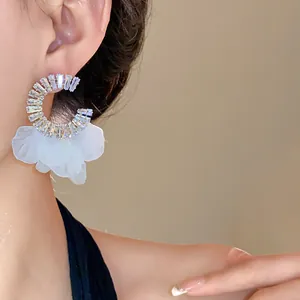 Primo piano di orecchini a cerchio in zircone con delicati petali di fiori bianchi