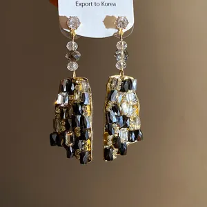 Dettaglio di orecchini pendenti vintage di lusso con cristalli neri e trasparenti
