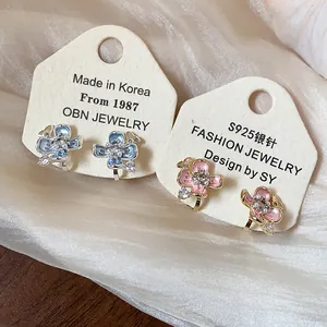 Macro detail of blue and pink enamel flower ear clips with sparkling zircon centers