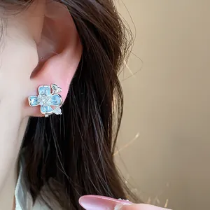 Detailed view of a sweet blue flower ear clip with butterfly motif on model's ear