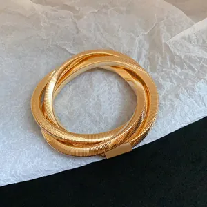 Detailed macro view of a golden spiral multi-layer metal bracelet with ribbed texture