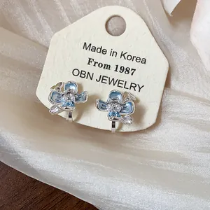 Detailed view of light blue flower clip-on earrings with pearls and crystals on display card