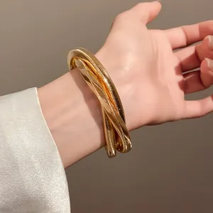 Close-up of golden intertwined spiral metal bracelet on model's wrist