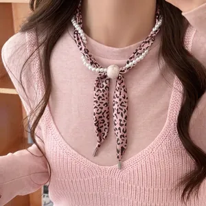Gros plan sur un collier élégant écharpe en soie léopard avec détails de perles