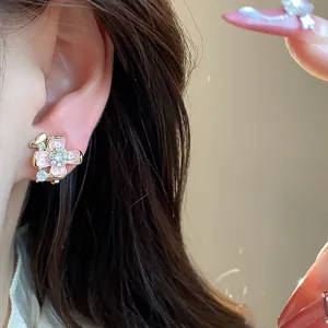 Detailed close-up of sweet pink flower clip-on earring with gold plating on model