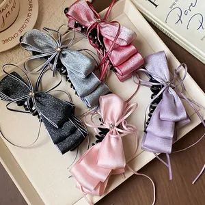 Detailed view of elegant multi-colored satin ribbon bow banana hair clips on a tray