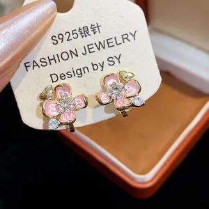 Close-up of 18k gold plated flower pearl ear clips with pink enamel and crystals