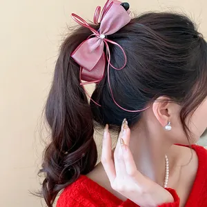 Professional close-up of an elegant pink ribbon bow banana hair clip on a ponytail style