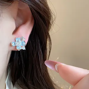 Detailed view of blue enamel flower ear clip with 18k gold plating worn on an ear