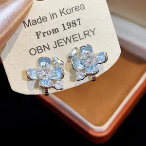 Close-up detail of light blue enamel flower clip-on earrings with pearls and crystals