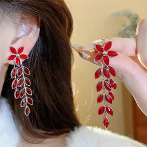 Close-up of red flower earrings with marquise-cut glass leaf tassels on a model