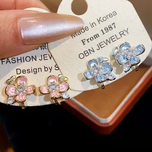 Detail view of floral ear clips with pearls and crystals on 18k gold plated finish