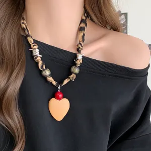 Vue détaillée d'un collier écharpe à motif léopard avec pendentif cœur sur un modèle.