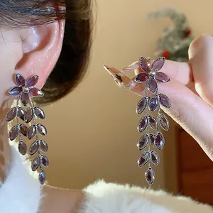 Close-up of elegant purple glass flower and leaf tassel earrings on an ear