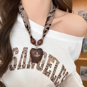 Gros plan d'un collier écharpe imprimé léopard avec pendentif cœur en bois siglé Orb
