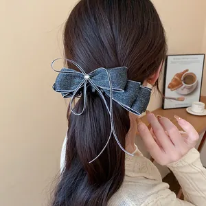 Detail of a dark grey glittery chiffon bow banana clip on a woman's ponytail.