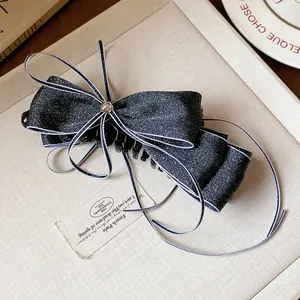 Close-up detail of an elegant black denim ribbon bow banana hair clip with star accent.