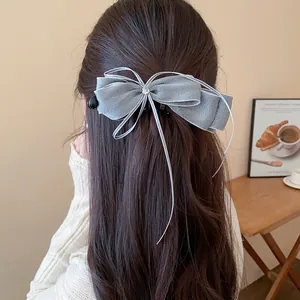 Grey chiffon bow banana clip hair accessory for women styled in long brown wavy hair