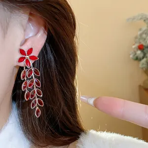 Elegant close-up shot of red glass flower and leaf tassel earrings worn by a model