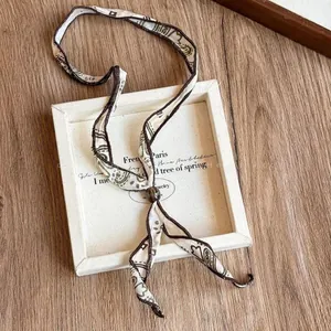 Vue détaillée d'un collier en foulard de soie à motif cachemire sur fond de bois.