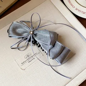 Detail view of an elegant silver ribbon bow hair clip with a small star rhinestone.