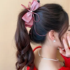 Detail shot of an exquisite pink satin bow hair clip on model ponytail for elegant styling