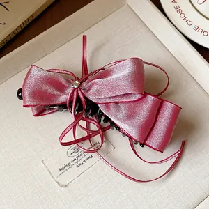 Detailed view of an elegant pink satin bow hair clip with a tiny star charm and long ribbons