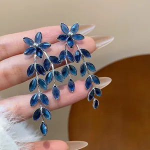 Detailed view of elegant blue glass flower and leaf tassel drop earrings with silver needles