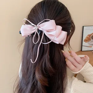 Detail of elegant pink satin bow hair banana clip worn on wavy hair.