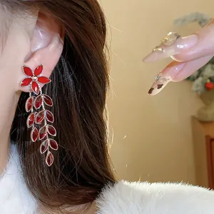 Close-up of elegant red glass flower and leaf tassel drop earrings on an Asian model