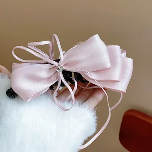 Close-up of elegant pink satin ribbon bow banana hair clip with rhinestone center