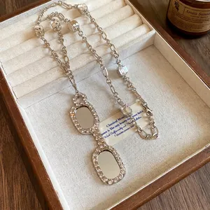 Elegant silver-toned necklace featuring a zircon encrusted glasses pendant in a display box