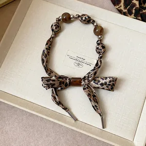 Détail d'un collier écharpe léopard avec d'élégantes perles brunes dans un coffret