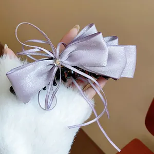 Detail of a lavender satin ribbon bow banana clip with rhinestone center.